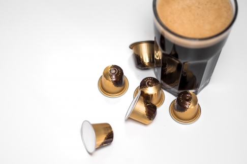 czarna kawa w otoczeniu kapsułek do automatycznego ekspresu